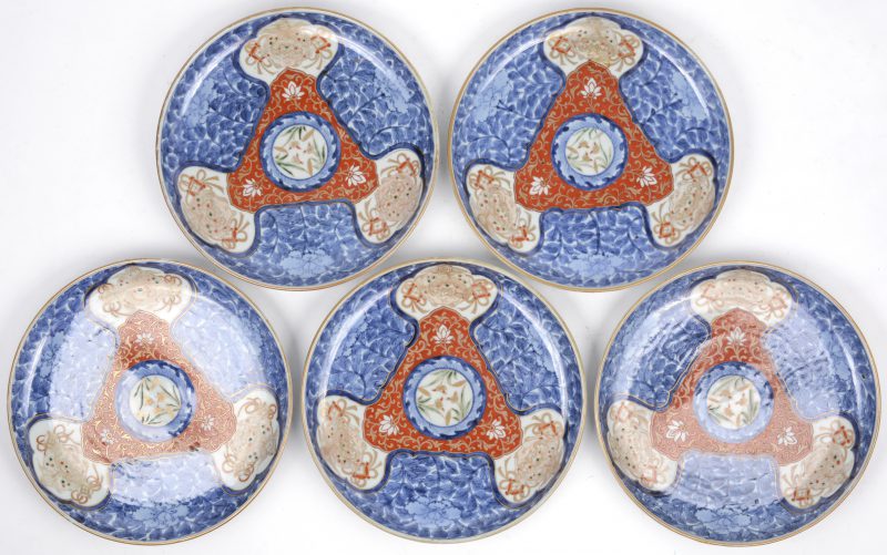 Een serie van vijf Arita borden met Chenghua merk. Imari decor met gestileerde fohonden in uitsparingen en met pioenen in blauw en wit rond een roestrode driehoek in het centrum rondom een rozet met polychrome bloemen. Japan, omstreeks 1780 volgens bijgevoegd certificaat van Yamanake & Co te Kyoto.