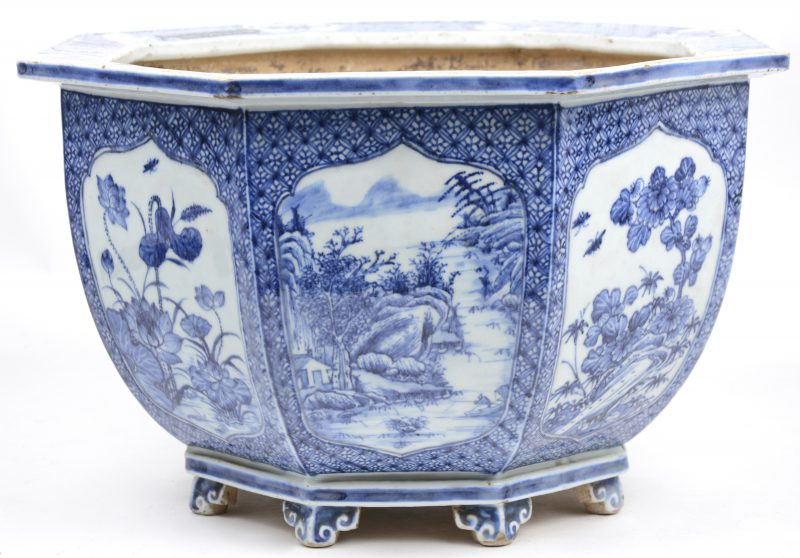 Een porseleinen achthoekige cachepot op acht krulpootjes en met blauw en witte decoratie van landschappen in acht uitsparingen. Chinees werk XIXde eeuw.