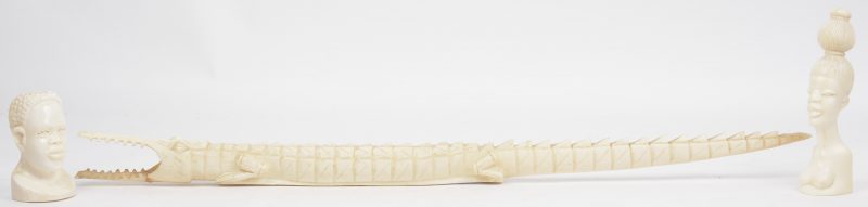 Twee kleine bustes en een krokodil van gebeeldhouwd ivoor. Afrikaans werk, eerste kwart XXste eeuw. Herstelling aan krokodil (L. 60 cm).