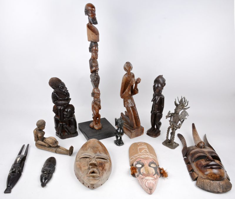 Twaalf stuks Afrikaanse kunst: beeldjes, maskers, een staf met hoofden van gebeeldhouwd hout, een stenen beeldje en een bronzen duiveltje.