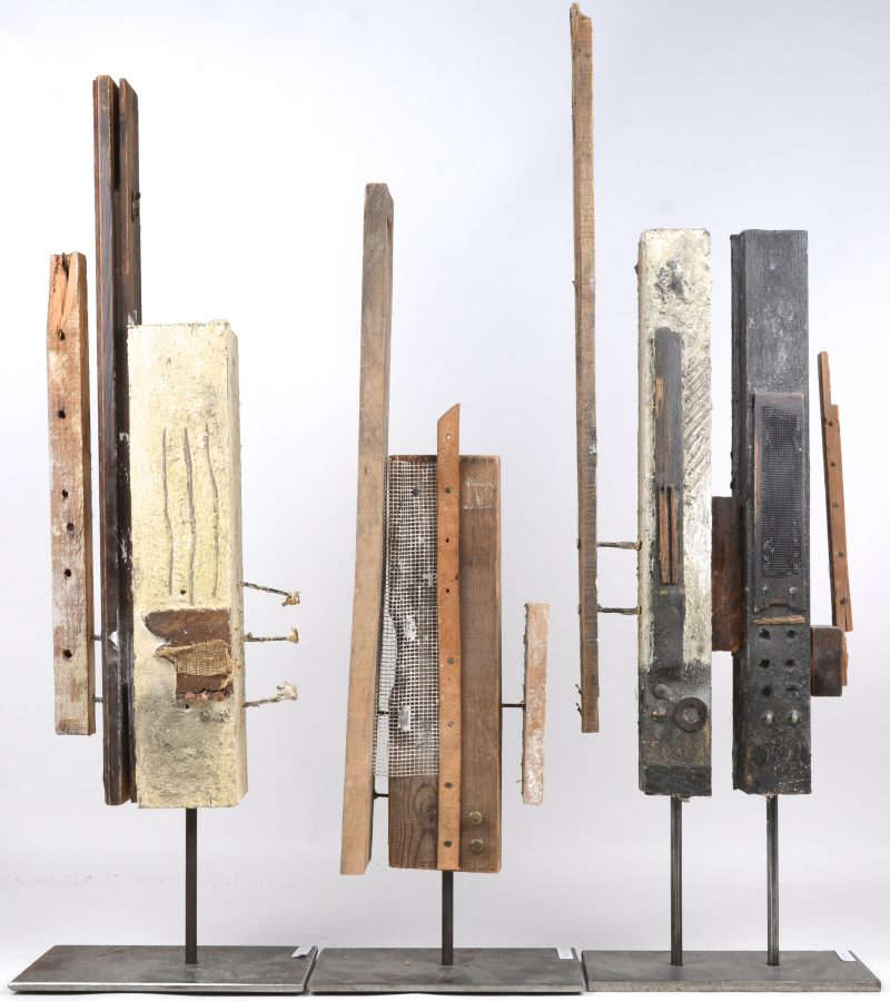 Drie moderne houten kunstwerken op metalen voetstukken.
