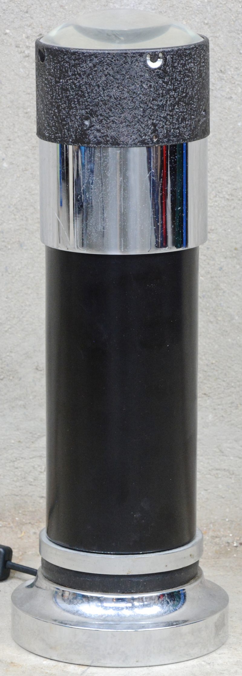 Een metalen lamp met bovenaan een bolle lens.