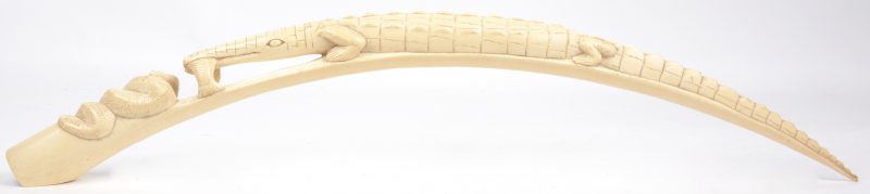 Een gesculpteerde Afrikaanse slagtand in de vorm van een krokodil met een vis en een slang.
