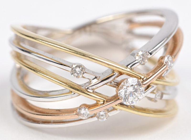 Een 18 karaats drie kleuren gouden ring bezet met briljanten met een gezamenlijk gewicht van ± 0,20 ct.