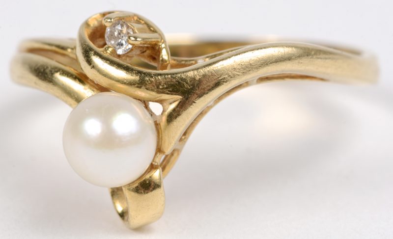 Een 18 karaats geel gouden ring bezet met één briljantje en een parel.
