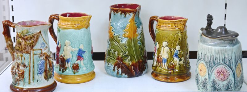 Een reeks van vijf Duitse kruiken van meerkleurig aardewerk met reliëfdecors.