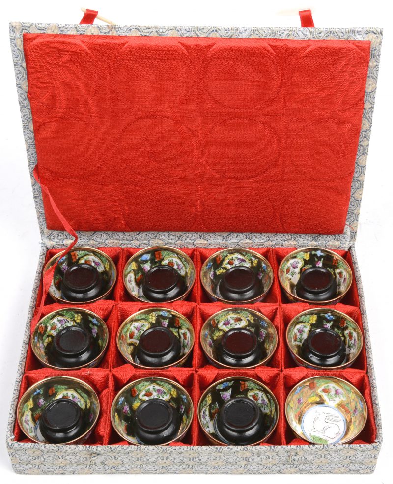 Een reeks van twaalf kopjes meerkleurig Chinees porselein. Op houten sokkeltjes en in originele doos.