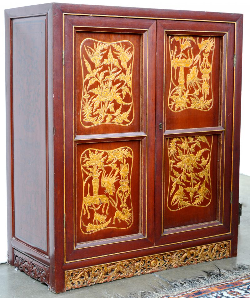 Een roodgelakt Chinees barmeubel met twee deuren en met spiegelglas binnenin.