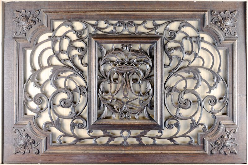 Een raamvoorzet van gebeeldhouwd hout. Centraal een monogram ‘M.A.’ onder een hertogelijke kroon. Omstreeks 1800.