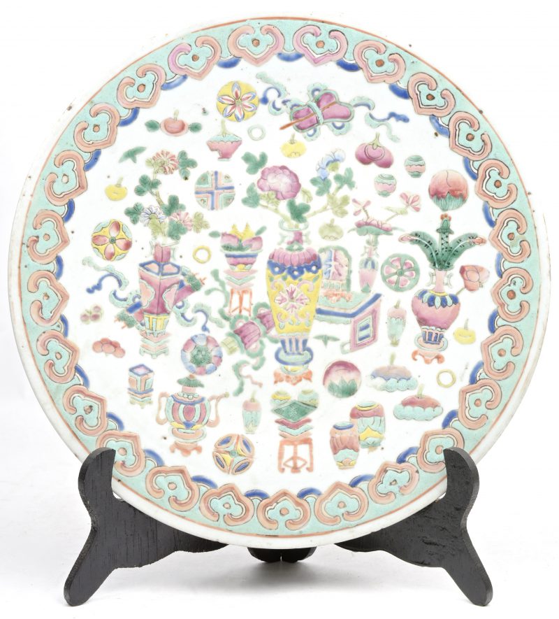 Een ronde schotel van polychroom Chinees porselein met decor van kostbaarheden. Einde XIXde eeuw.