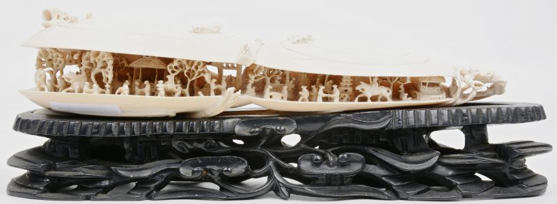 Een sculptuur van ivoor met voorstelling van twee mosselschelpen, waarin talrijke minuscule personages in een landschap. Op gebeeldhouwde zwarte houten sokkel. Een schaar van een krab ontbreekt. China, begin XXste eeuw.