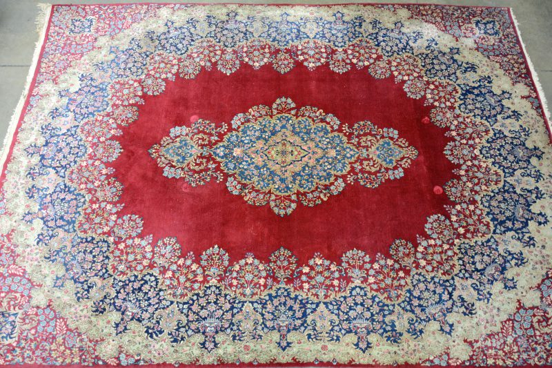 Een handgeknoopt Perzisch wollen tapijt met bloemenmotieven en een centraal medaillon.