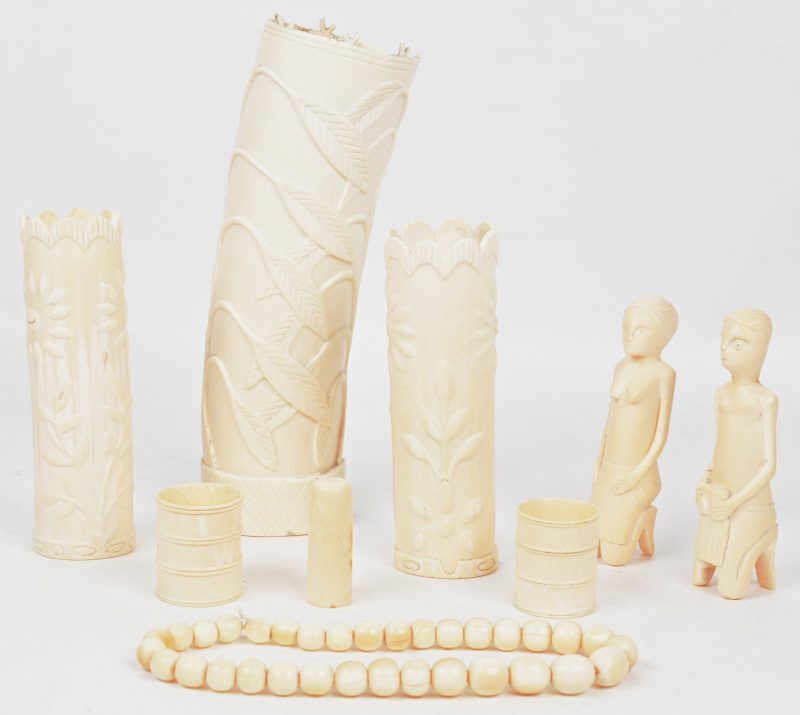 Een lot gesculpteerd ivoor uit  de eerste helft van de XXe eeuw, bestaande uit drie vaasjes, twee beeldjes, twee servetringen en een paternoster.