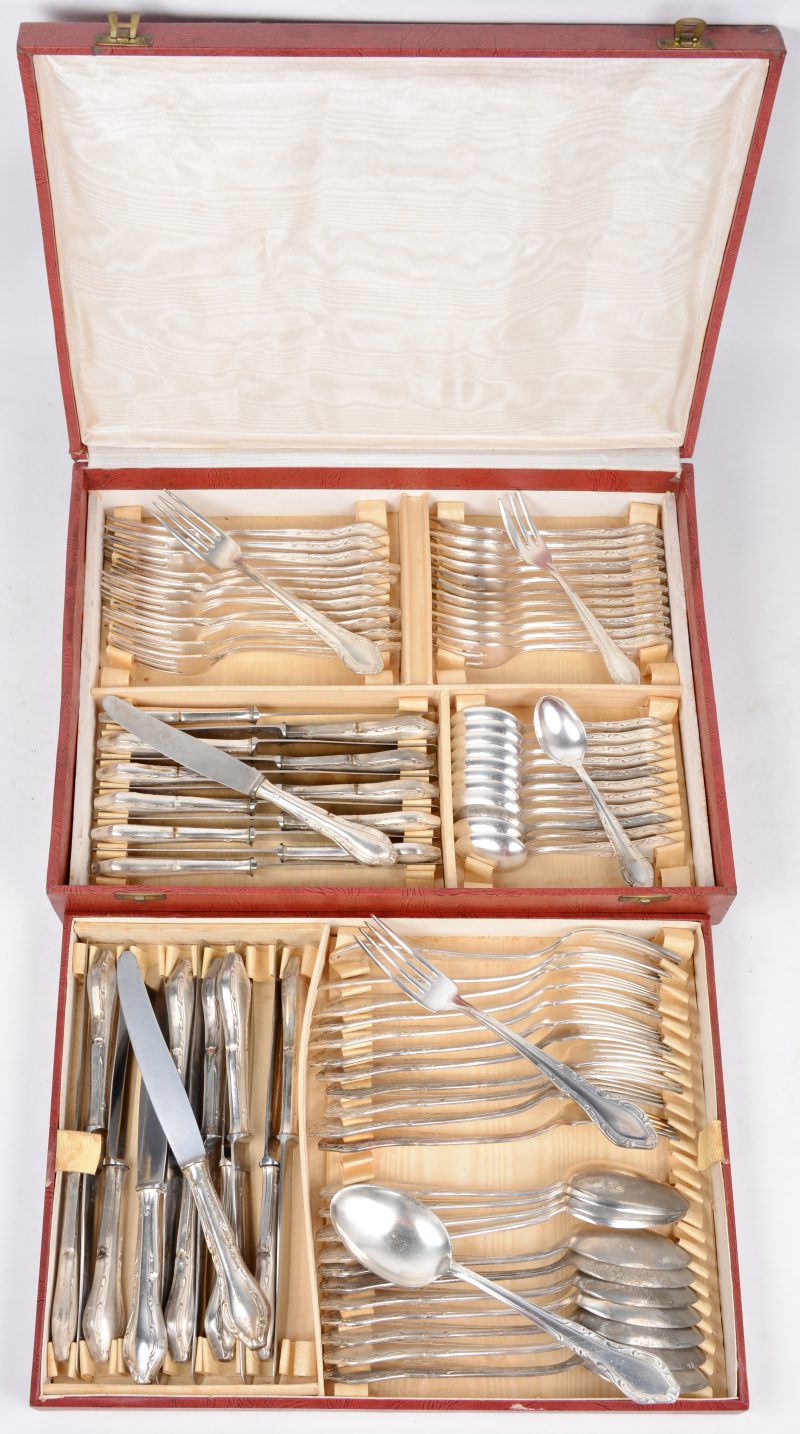 Een verzilverd metalen bestek, bestaande uit kleine vorken en messen, grote vorken, messen en lepels, koffielepels en desservorkjes. Compleet voor twaalf personen en in koffer.