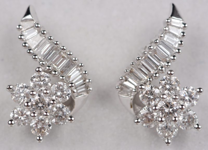 Een paar 18 karaats wit gouden oorbellen bezet met diamanten en baguetten met een gezamenlijk gewicht ± 0,74 ct.