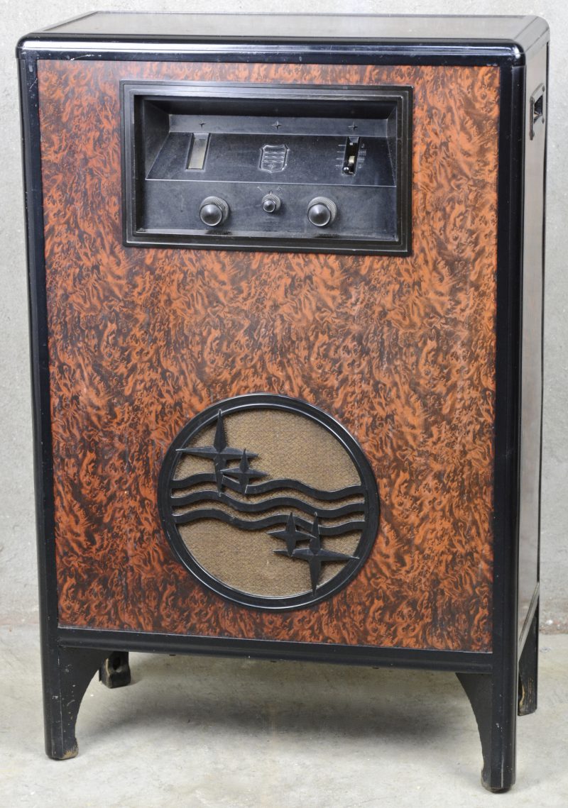 Een oude staande radio in kast van metaal en bakeliet.