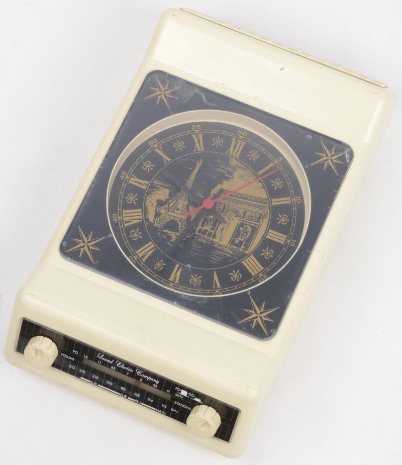 Een klokradio, model ‘sound time’ met een afbeelding van de Eiffeltoren en de Arc de Triomphe op de wijzerplaat.