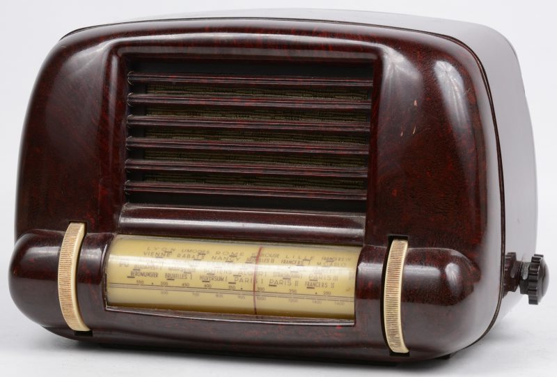 Een vintage radio in bakelieten kast. Enkele bevestigingspunten achteraan doorgebarsten.