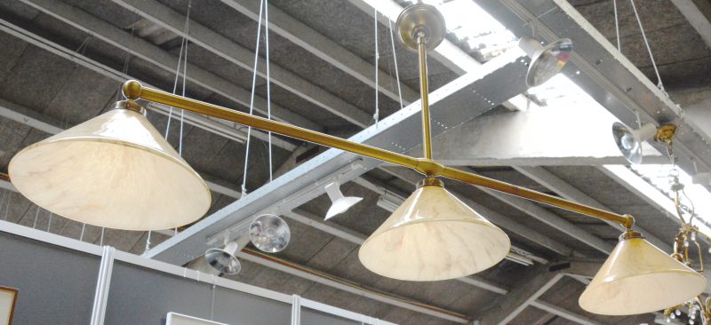 Een vintage hanglamp met drie gekleurde glazen kappen aan messingen frame.