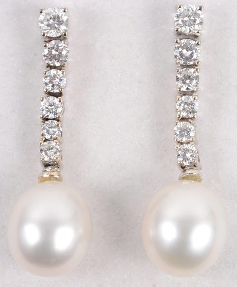 Een paar 18 karaats wit gouden oorbellen bezet met een briljanten met een gezamenlijk gewicht van ± 1,30 ct. en twee parels.