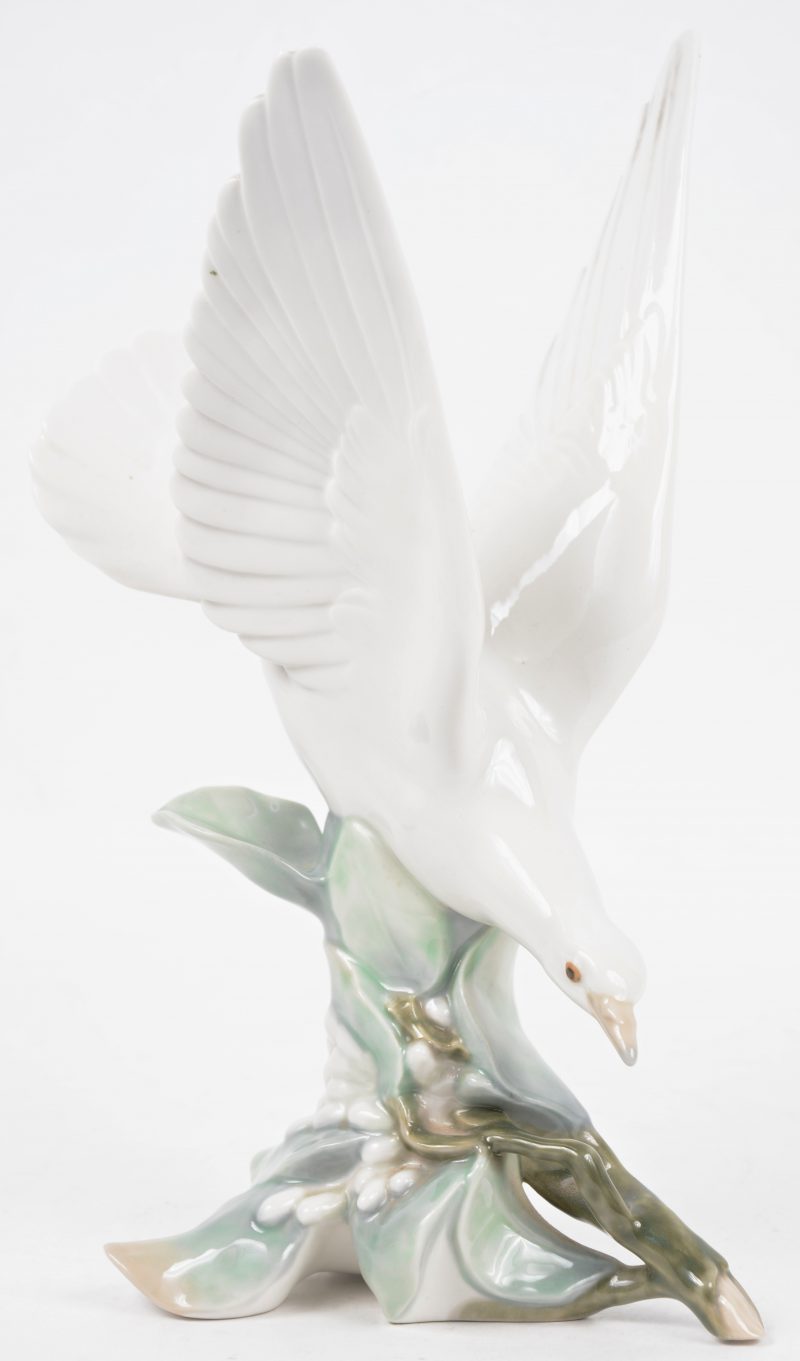 Een polychroom porseleinen beeld van een duif in vlucht.