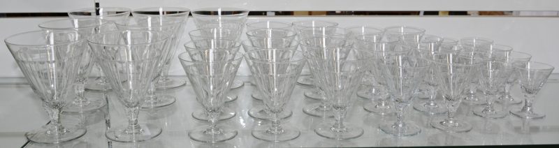 Een art deco glazenservies van geslepen kleurloos kristal, bestaande uit 7 grote glazen, 11 rodewijnglazen, 8 wittewijnglazen en 8 aperitiefglazen.