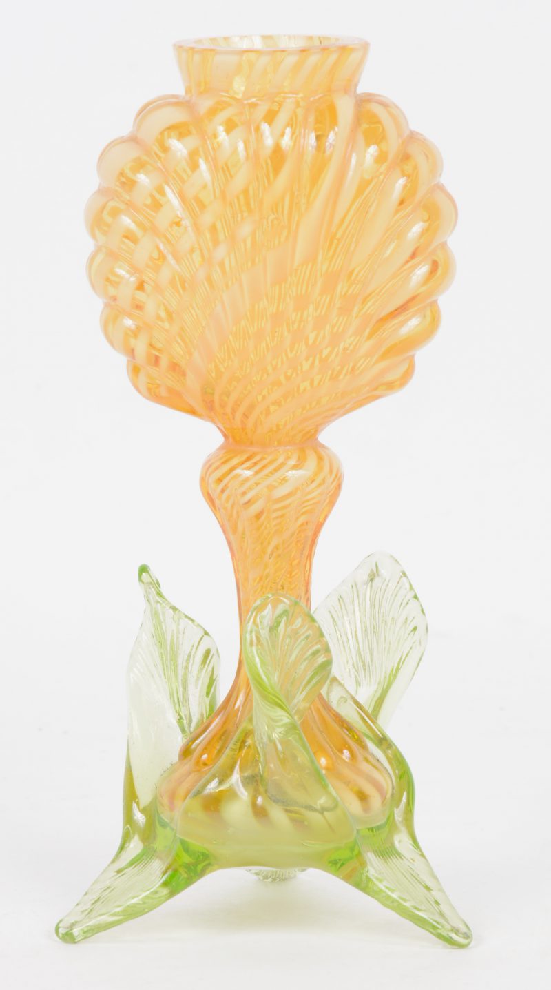 Een siervaasje van geel en groen Muranoglas met een voet in de voet van bladeren.