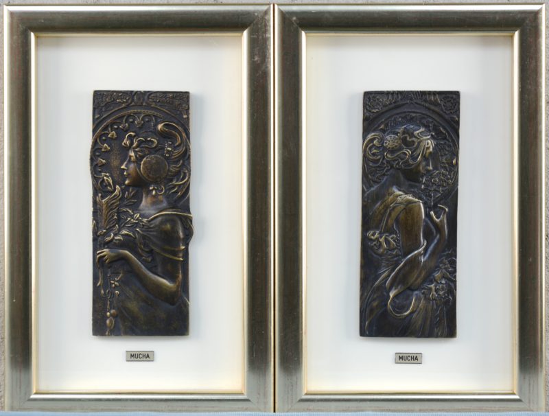 Een paar bronzen plaquettes met art nouveau vrouwenprofielen in reliëf naar ontwerpen van Alphonse Mucha.