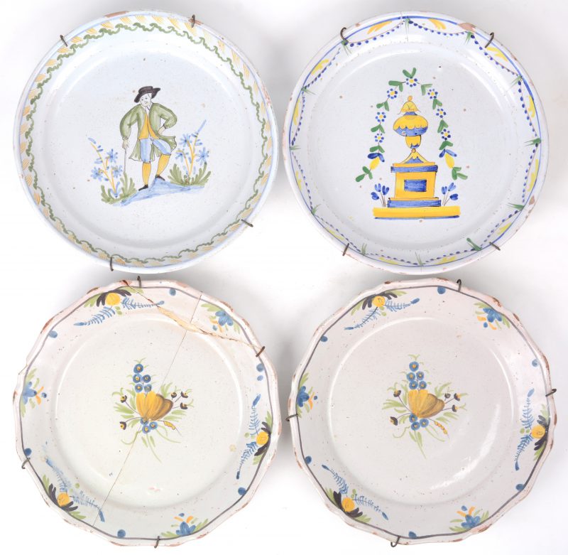 Een lot van vier borden van Delfts aardewerk met meerkleurige decors. Eén gerestaureerd. XIXe eeuw.