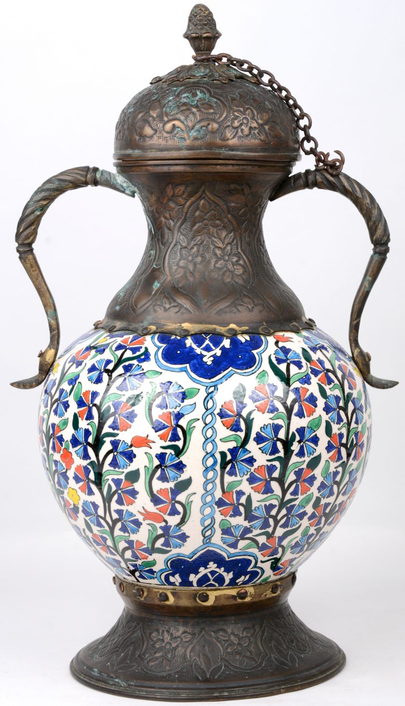 Een dekselvaas van meerkleurig aardewerk met voet, monturen en deksel van gedreven koper. Mogelijk Perzisch.