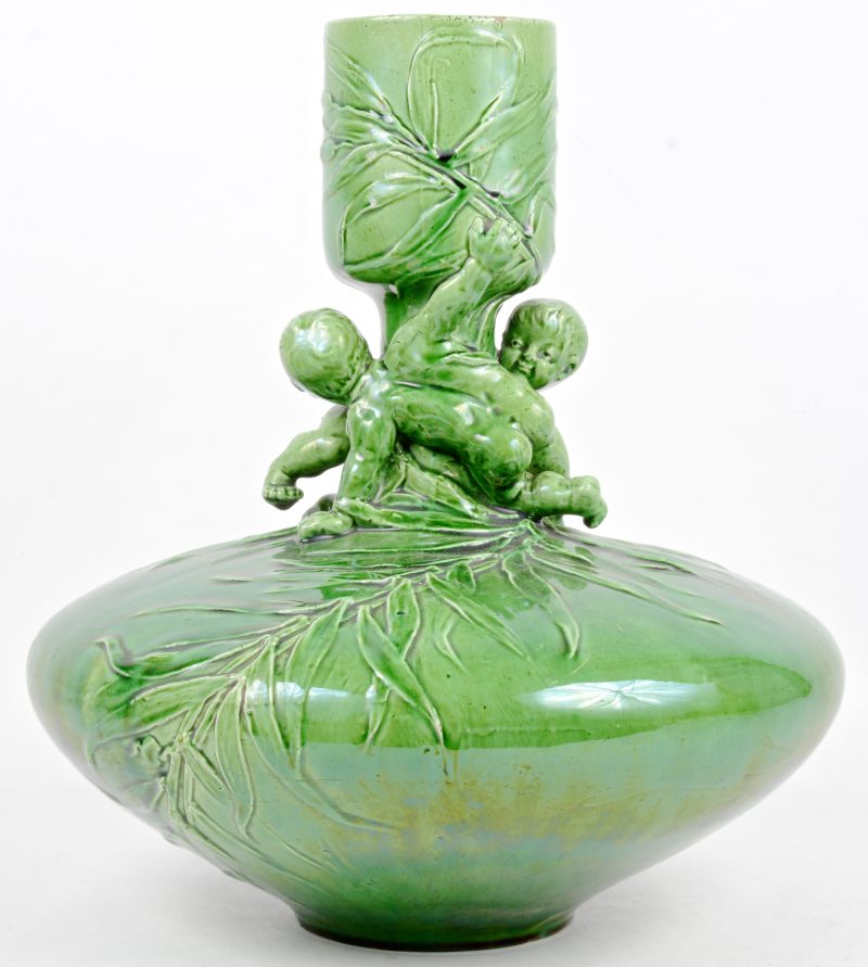 Een groene aardewerken vaas met een decor van takken en spelende kinderen.