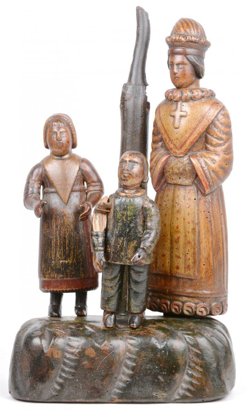 Een beeldengroep van gebeeldhouwd en gepolychromeerd hout met drie personages. Omstreeks 1800.