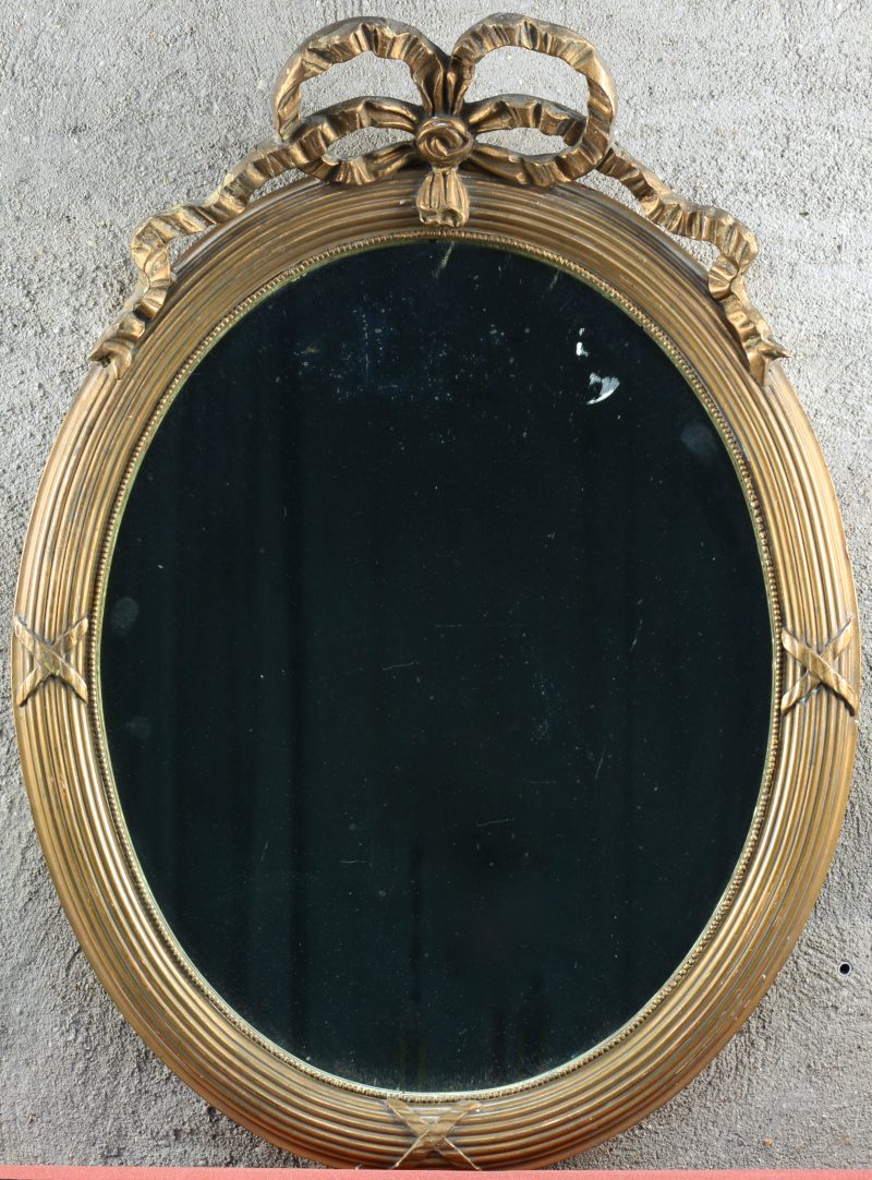 Een spiegel in verguld houten lijst, versierd met een kuif in de vorm van een strik.