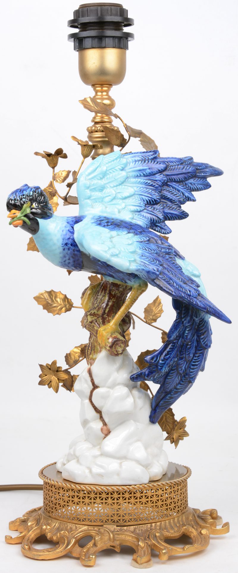 Een lampenvoet, versierd met messingen blaadjes en een vogel van meerkleurig porselein.