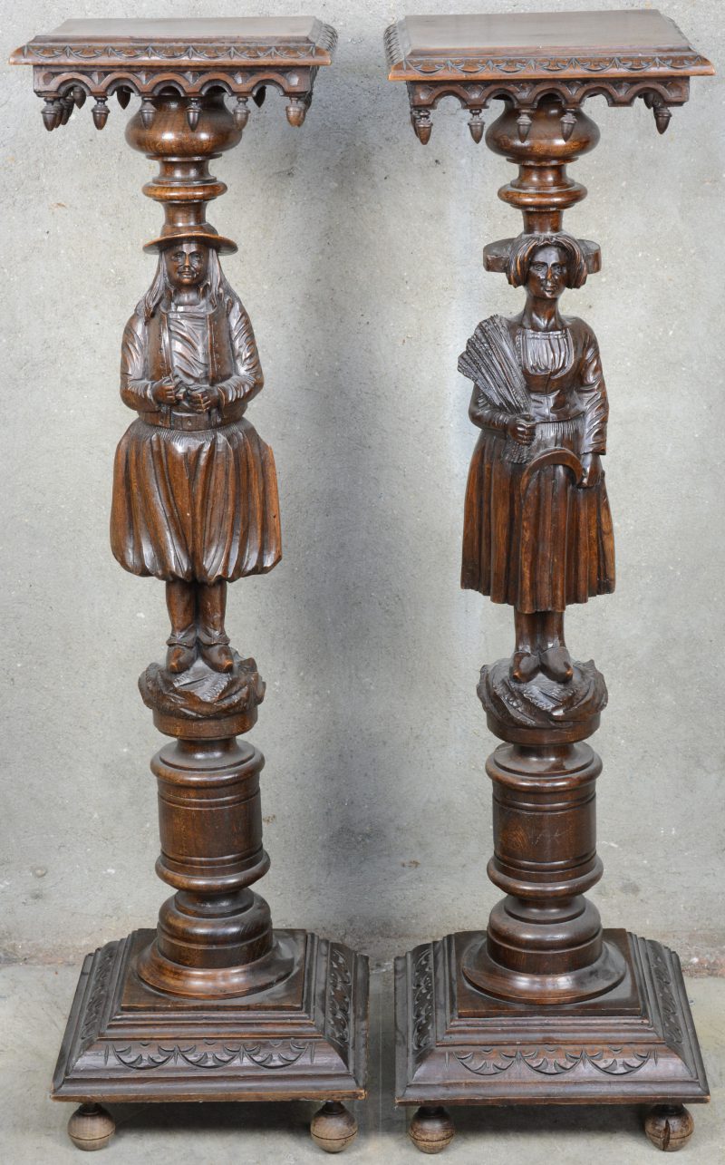 Twee gebeeldhouwde eikenhouten pioedestals in de vorm van een man en een vrouw.