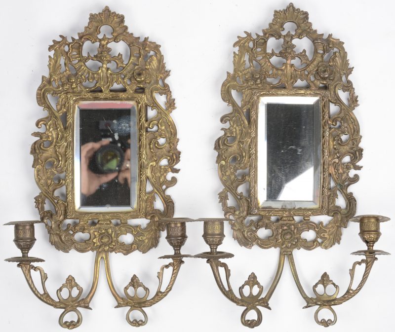 Een paar barokke koperen wandspiegels met telkens twee kaarsenhouders. Rocaillemotieven. Geslepen spiegelglas