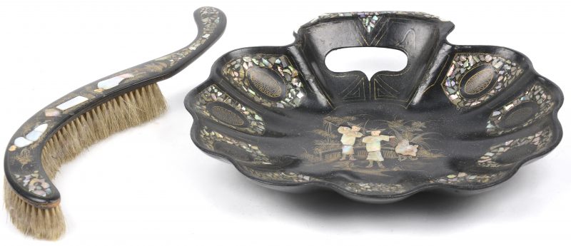Een tafelschuier en blik in de vorm van een schelp. Zwart hout ingelegd met parelmoer en versierd met vergulde personages. Chinees werk.
