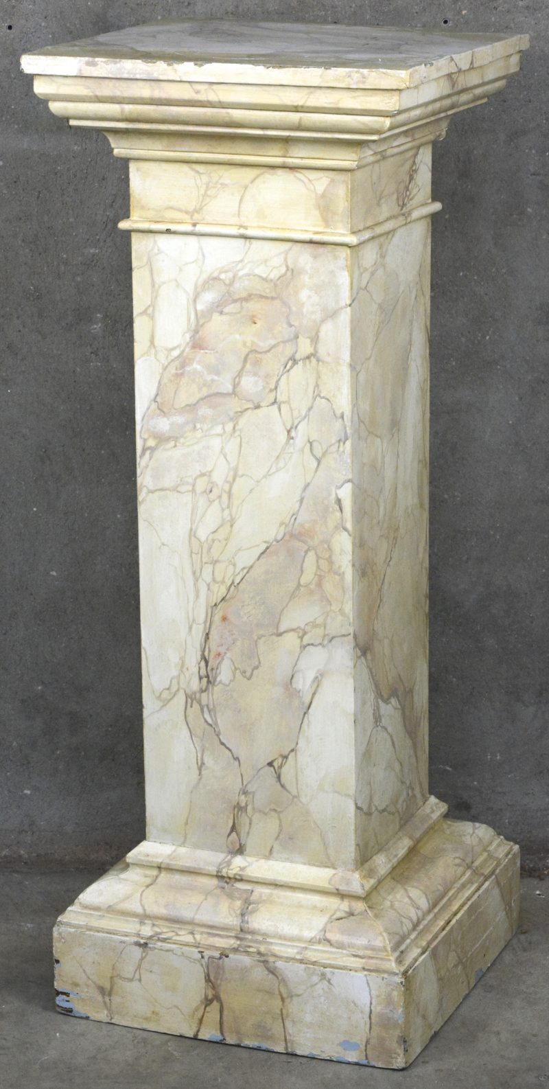 Een houten zuil met vierkante doorsnede, beschilderd in faux marbre.