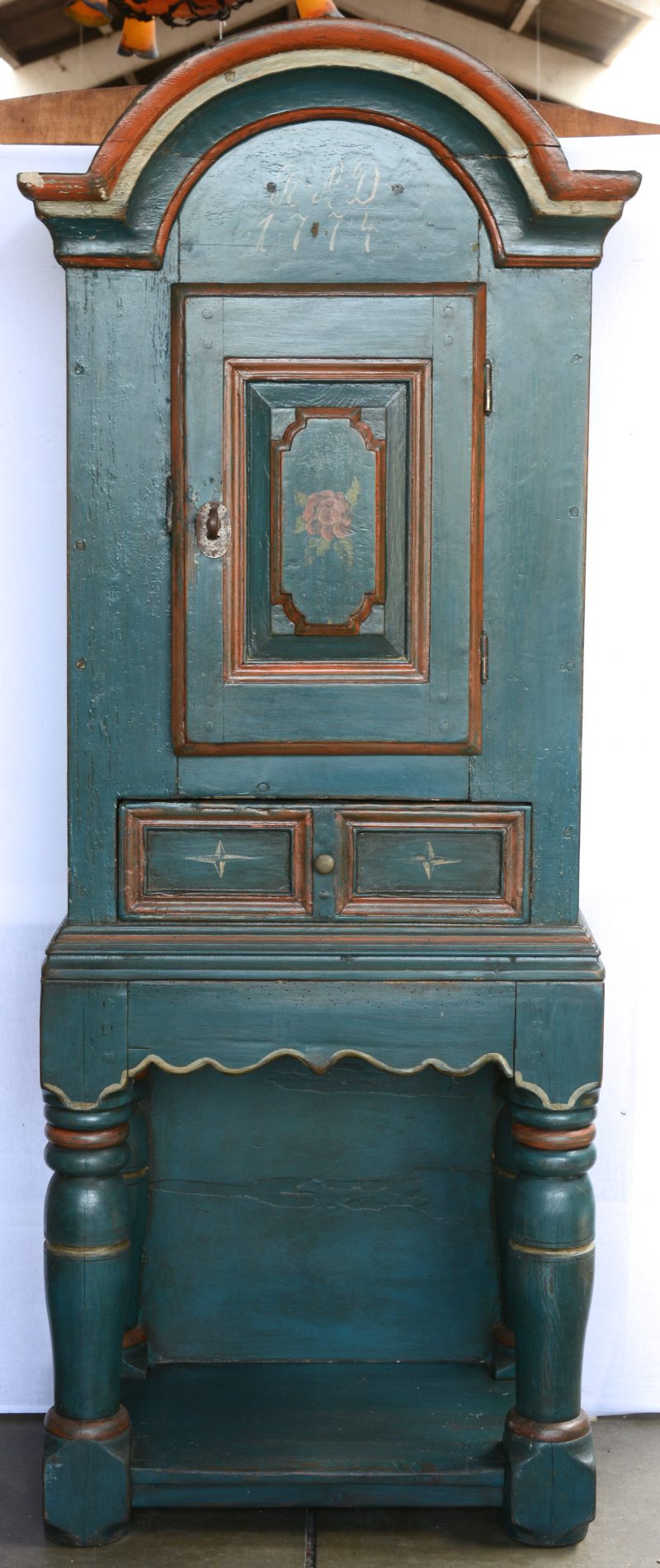 Een tweeledige groengepatineerde credenza met een deurtje en een lade. Gedateerd 1774.