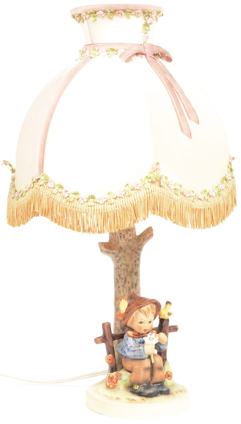 Een lampvoetje van meerkleurig porselein in de vorm van een jongetje met een bloem op een bankje bij een boom. Gemerkt.h