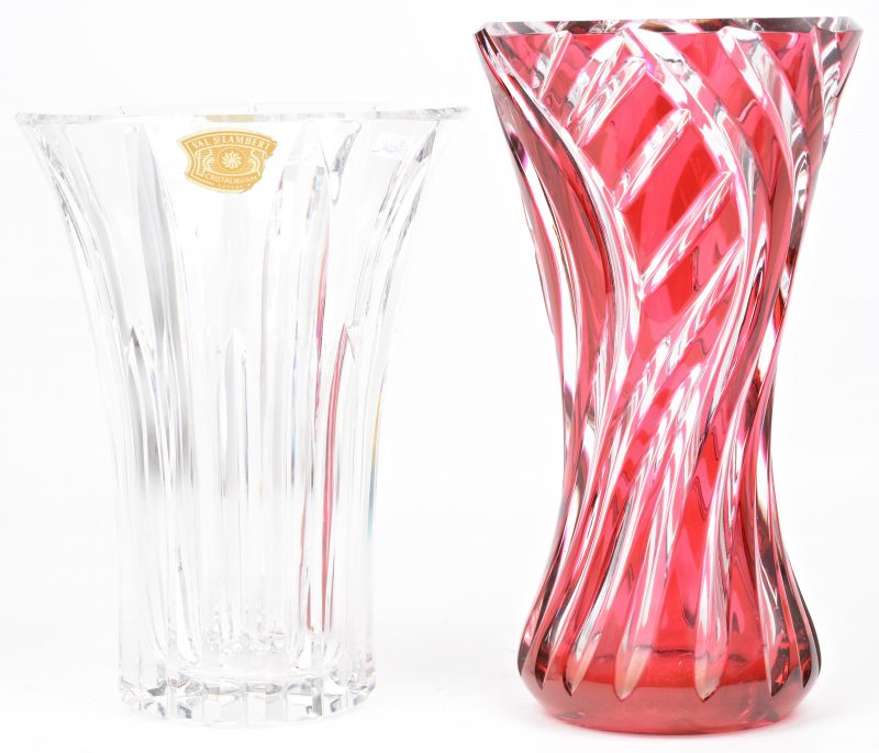 Twee vazen van gslepen kristal, de éne kleurloos, de andere rood gekleurd in de massa. Beide met gegraveerd merk onderaan, de eerste eveneens met etiket.
