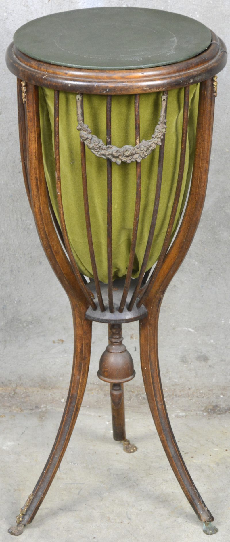 Een gebogen houten naaitafeltje op drie poten en met fluwelen voering.