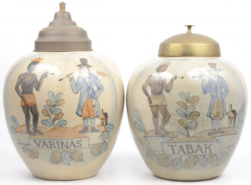 Een paar aardewerken tabakspotten in licht verschillende formaten met dezelfde decors, de één met opschrift ‘Varinas’ en de andere met opschrift ‘Tabak’. Met messingen deksels. XIXe eeuw.