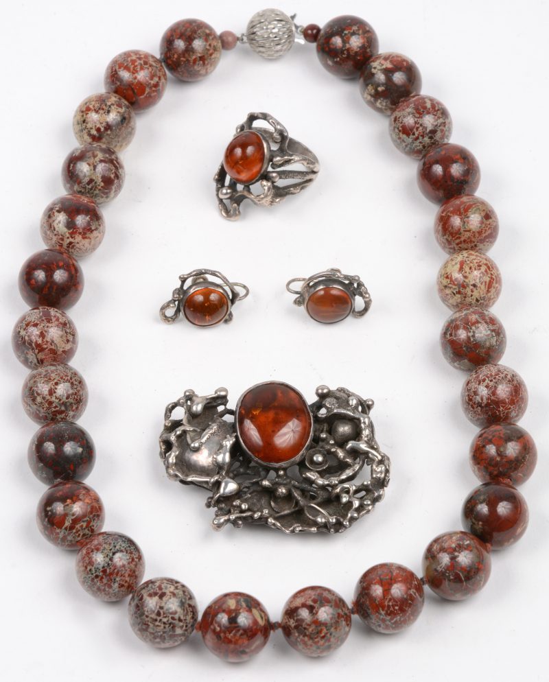 Een halssnoer met kralen van jaspis en een broche met bijpassende ring en oorbellen van zilver bezet met amber.
