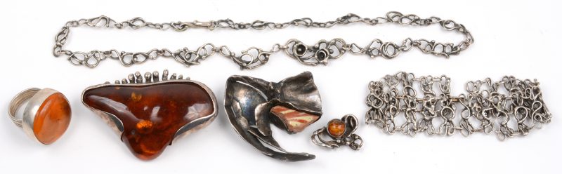 Drie verschillende broches en een ring bezet met amber en een halssnoer met bijpassende armband van zilver.