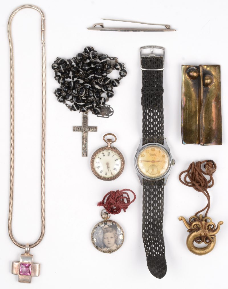Een zilveren zakhorloge, fotohanger, speld en een ketting met hanger in de vorm van een kruis. We voegen er een herenhorloge gemerkt Cortébert een paternoster en een broche en hanger aan toe.