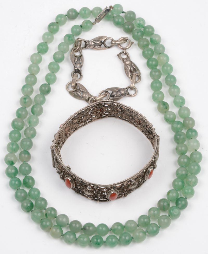 Een halssnoer van jadeite kralen met zilveren slot en twee armbanden van zilver één ervan bezet met koraal.