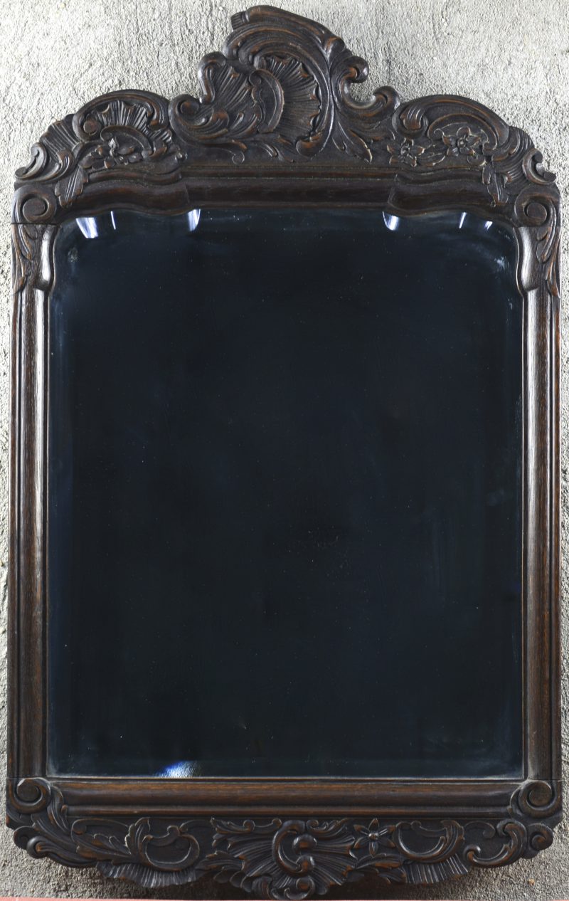 Een spiegel van gesculpteerd hout in barokke stijl.