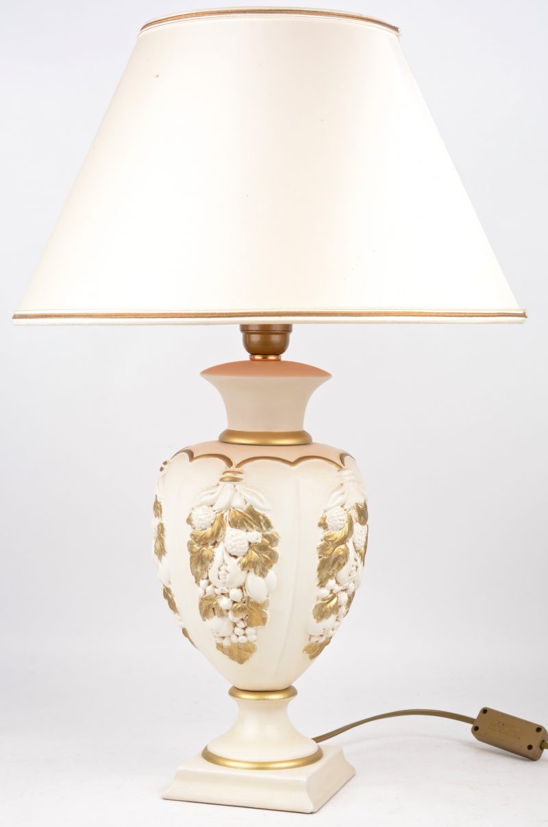 Een lampenvoet van wit- en goudgepatineerd plaaster of terracotta. Achteraan gemerkt.