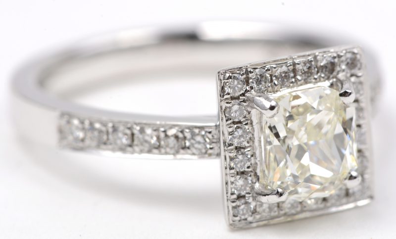 Een 18 karaats wit gouden ring bezet een centrale diamant van ± 1,05 ct. J. VSI. en briljanten met een gezamenlijk gewicht van ± 0,32 ct.